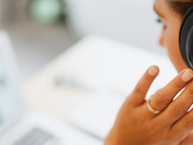 Woman at home using headphones and laptop for online work or video call.